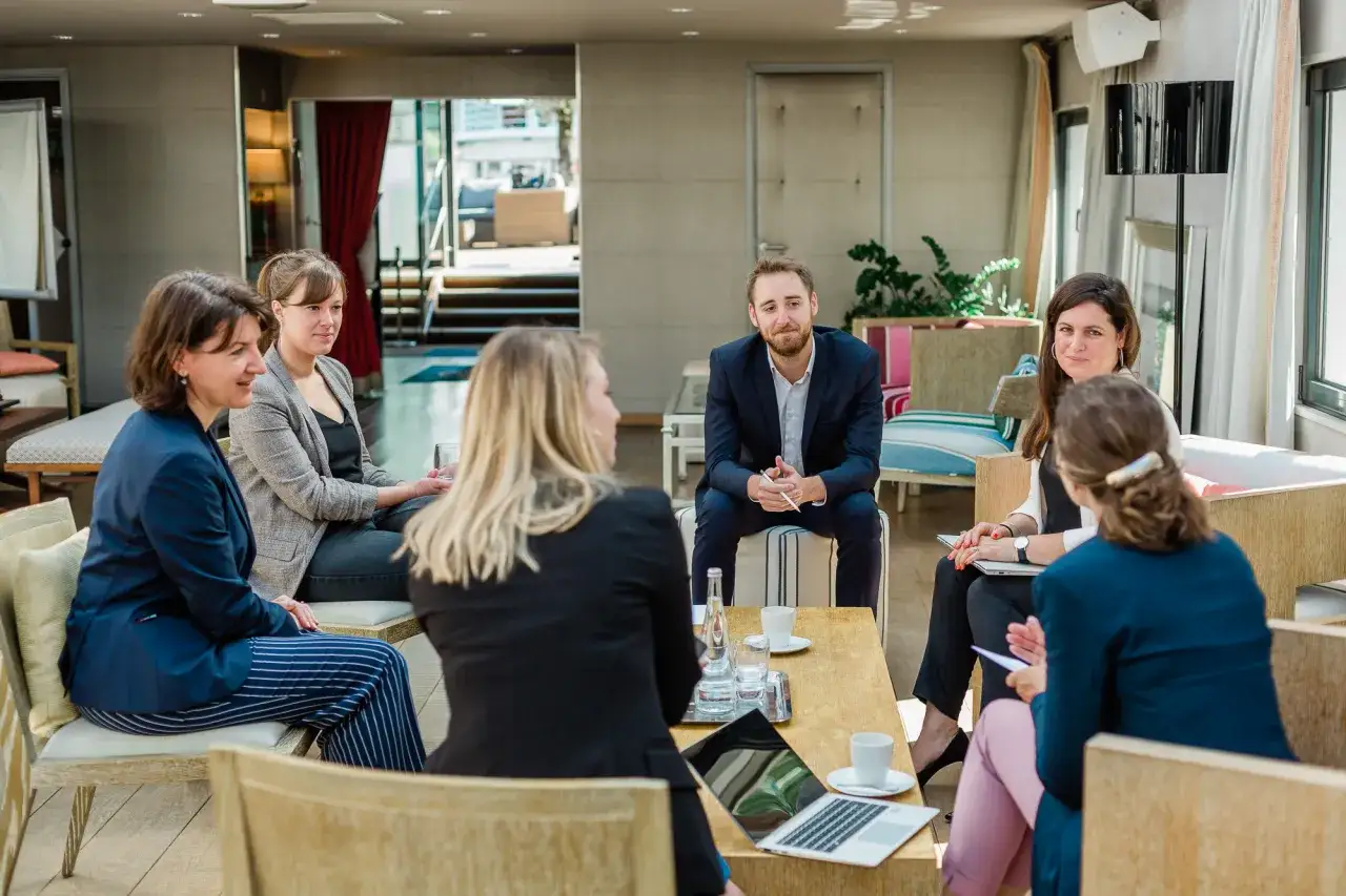 Des employ&eacute;s discutent autour d'une table lors d'un programme s&eacute;minaire entreprise.
