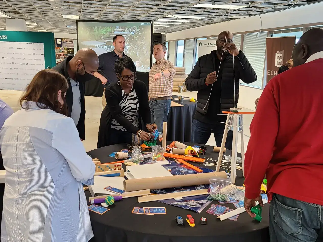 Des participants engagés dans une activité de groupe, construisant des objets avec des matériaux variés.