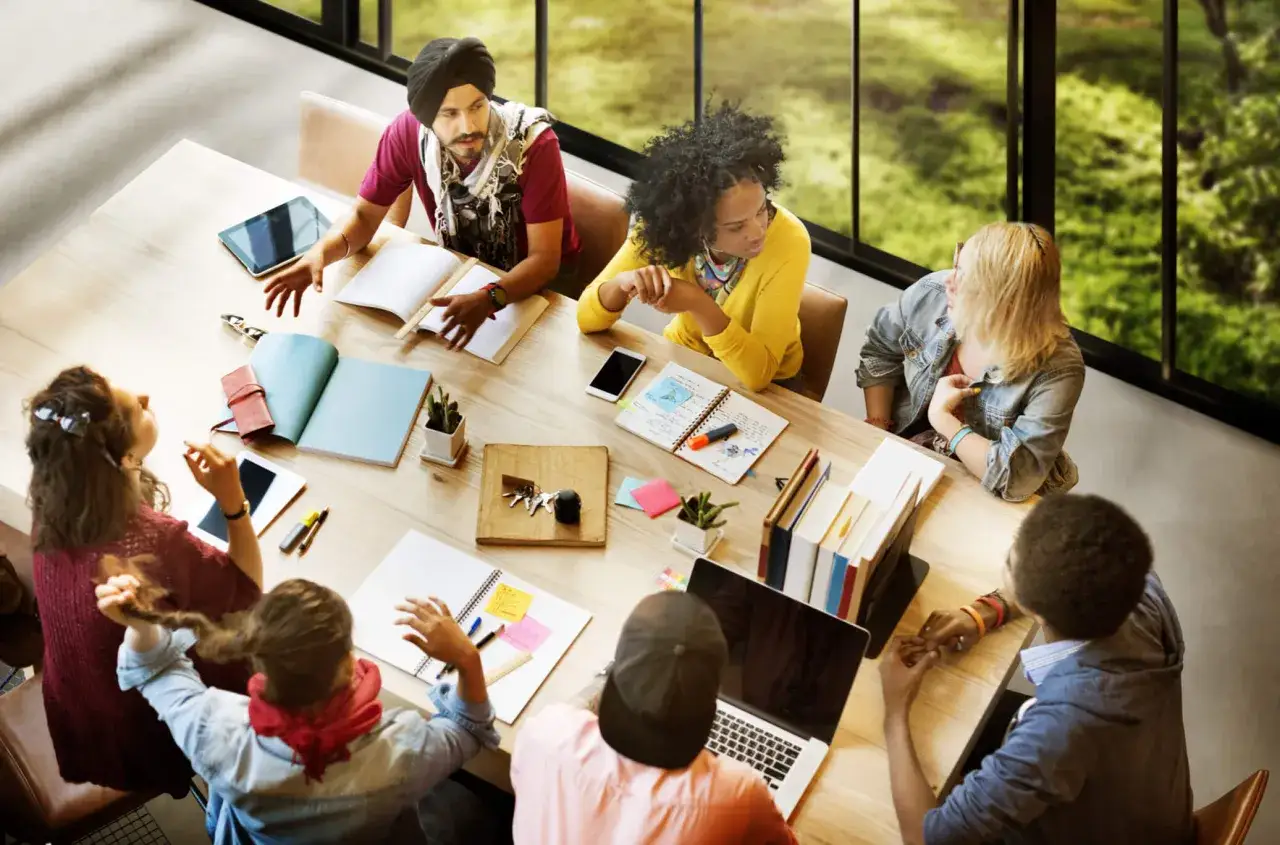 Une équipe diverse discute autour d'une table, démontrant une excellente qualité de chef de projet dans la collaboration.