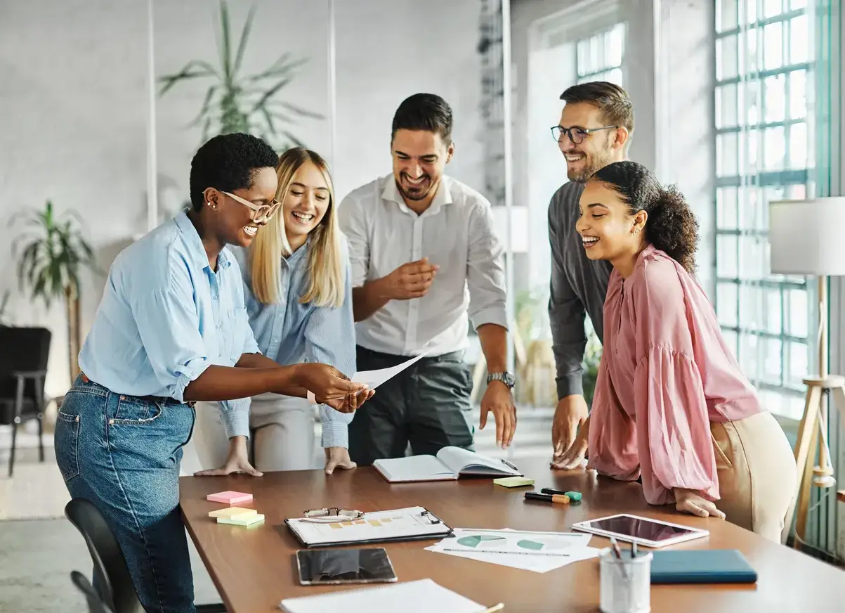 Une &eacute;quipe souriante autour d'une table, partageant des documents. Un vrai levier de motivation pour ce projet !