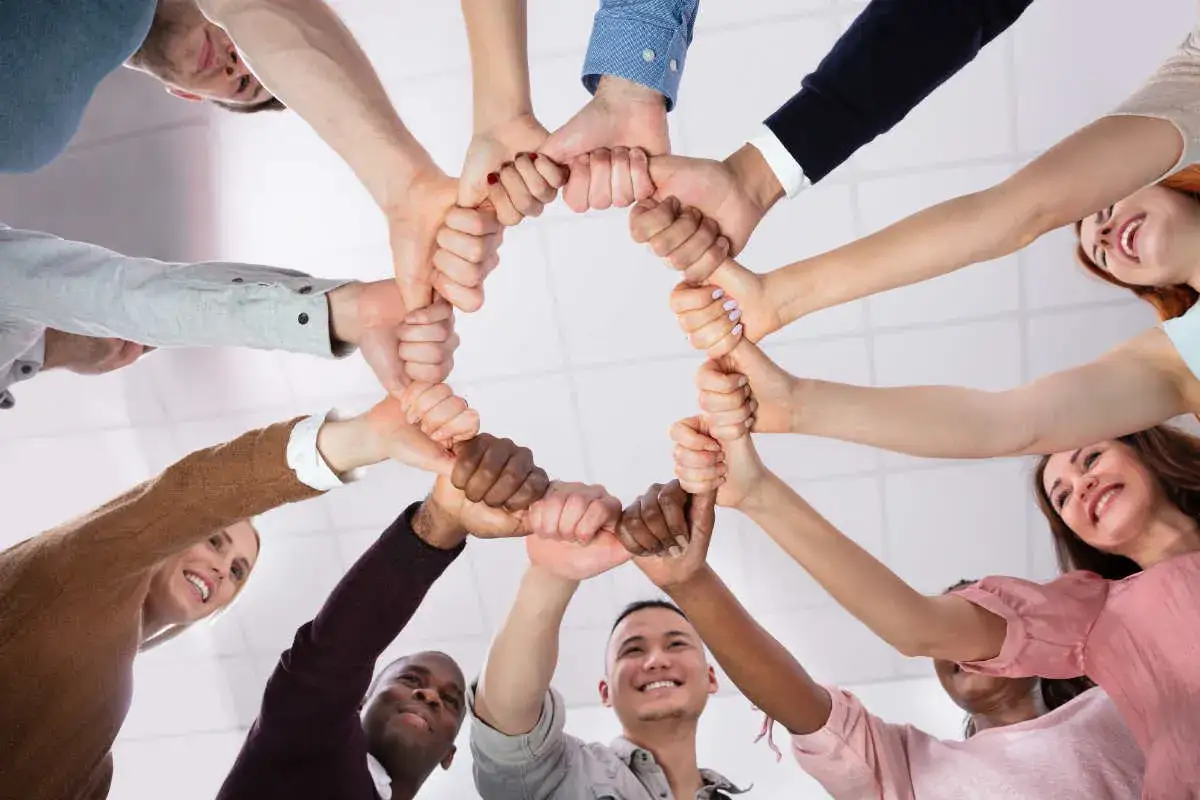 Un groupe de travail uni forme un cercle avec leurs mains, symbolisant la collaboration et la confiance.