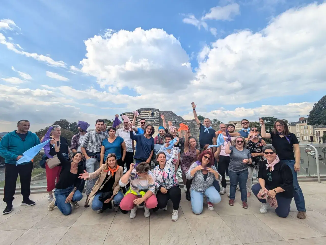Un groupe joyeux agite des foulards color&eacute;s sous un ciel bleu. Une belle id&eacute;e s&eacute;minaire pour renforcer l'esprit d'&eacute;quipe !