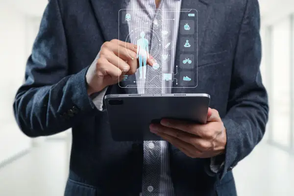 Un homme en costume utilise une tablette pour visualiser un tableau de bord de santé, marquant la cloture de projet.