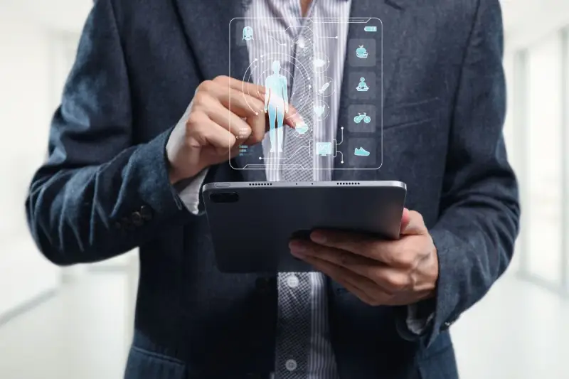 Un homme en costume utilise une tablette pour visualiser un tableau de bord de santé, marquant la cloture de projet.