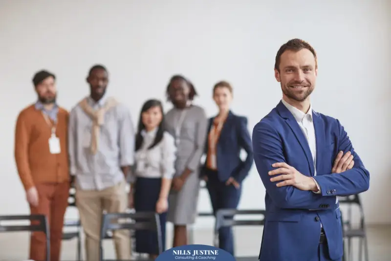 Un homme d'affaires souriant, qui semble avoir du charisme, pose devant son équipe.