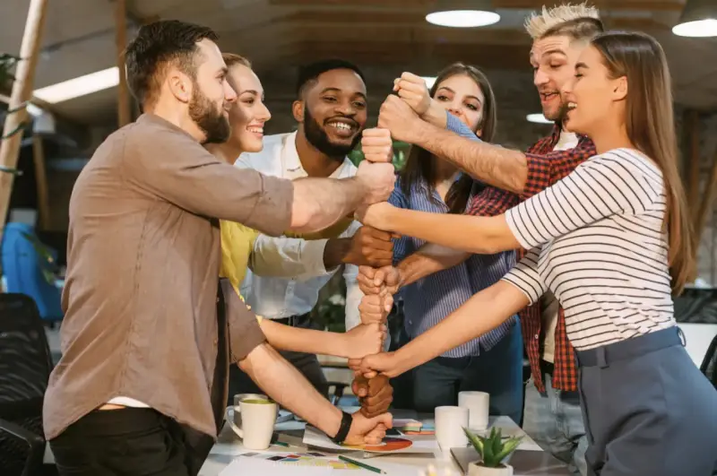 Une équipe soudée célèbre un événement team building, unissant leurs poings pour symboliser la force collective et la réussite.